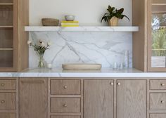 a kitchen with marble counter tops and wooden cabinetry, along with flowers in vases