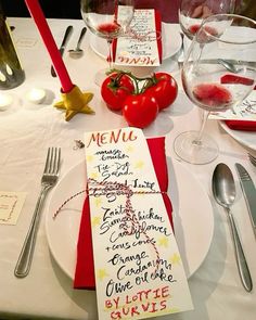 a place setting with red napkins, silverware and wine glasses on the table