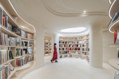 a woman in a red dress walking through a library filled with books