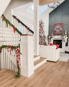 the stairs are decorated with christmas garlands and red bows for holiday decor in this living room