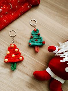 two crocheted christmas tree keychains sitting next to each other on a table