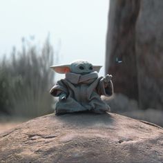 a baby yoda figurine sitting on top of a rock