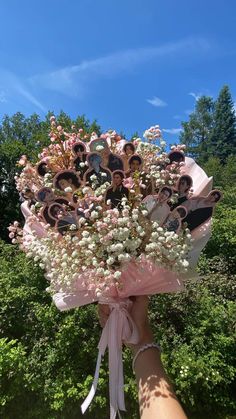 a bouquet of flowers is being held up by someone's hand with the sky in the background