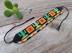 two beaded bracelets on a wooden table next to a succulent plant