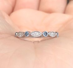 a woman's hand holding a diamond and blue topaz ring