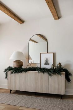 a dresser with a mirror, lamp and christmas decorations on it in a living room