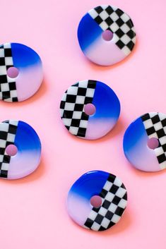 four blue and white checkered buttons sitting on top of a pink surface with one button missing