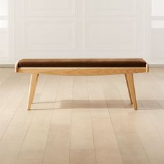 a wooden bench sitting on top of a hard wood floor next to a white wall