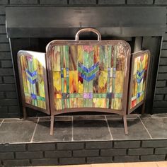 a colorful piece of art sitting in front of a fire place