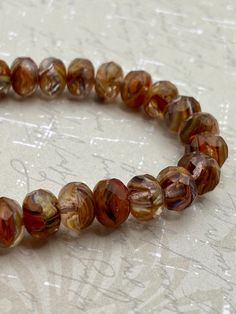 a close up of a beaded bracelet on a table with writing in the background