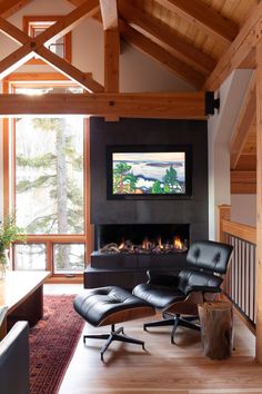 a living room with a fireplace, chair and large screen tv in it's center