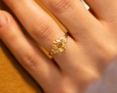 a close up of a person's hand with a ring on their finger and a yellow diamond in the middle