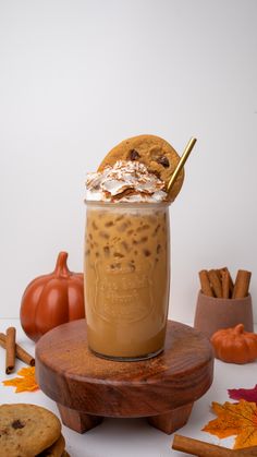 there is a drink with whipped cream and cookies on the table next to pumpkins