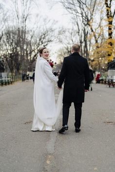 a bride and groom are walking down the street holding hands in front of each other