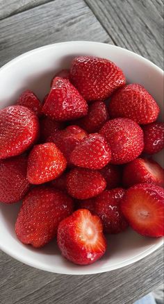 a white bowl filled with lots of ripe strawberries