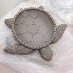 a clay turtle sitting on top of a plastic bag