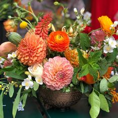 a vase filled with lots of different colored flowers on top of a green tablecloth