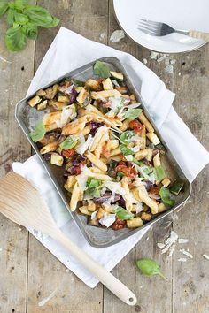 a pan filled with pasta and vegetables on top of a wooden table