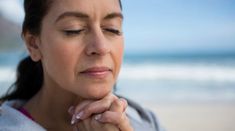 a woman with her eyes closed on the beach