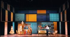 three people standing on stage in front of furniture