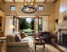 a living room filled with furniture and a chandelier hanging from the ceiling over a fire place