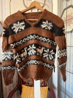 This super soft sweater was made by hand from a wool blend in medium brown and black, accented by various designs in light beige. The measurements, taken with the sweater lying flat, are: shoulder to shoulder, 18 inches; armpit to armpit, 20 inches; sleeves, 22 inches; length, 20 inches; bottom edge, 13 inches (with stretchy ribbing). In very good condition. Brown Knit V-neck Sweater For Winter, Brown Knitted V-neck Sweater, Cozy Brown Knit V-neck Sweater, Cozy Knitted Brown Sweater, Hand Knitted V-neck Winter Sweater, Hand Knitted V-neck Sweater For Winter, Brown Fair Isle Sweater For Fall, Vintage Brown Sweater With Fair Isle Pattern, Brown Nordic Sweater For Fall