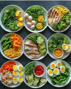 several plates filled with different types of food on top of a table next to eggs and broccoli