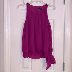 Sleeveless Blouse With Pleading Around Neckline Has Band At The Bottom And Ties In A Bow. The Back Is Keyhole With A Button Closure, Size Small, New With Tags Has An Extra Button, Pit To Pit Measurements 18 Inches Are Approximately Chic Purple Tank Top For Spring, Purple Tank Camisole For Spring, Purple Casual Tank Top For Party, Elegant Purple Camisole For Summer, Purple Camisole Top For Spring, Casual Purple Tank Top For Party, Purple Tank Top For Spring, Purple Sleeveless Tops, Purple Halter Neck Top For Summer