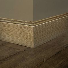 the corner of an empty room with wood flooring and gray walls in the background