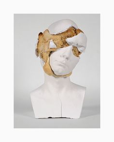 a white mannequin head with a piece of bread in it's mouth