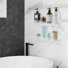 a white bath tub sitting next to a wall mounted shelf filled with soap and lotion