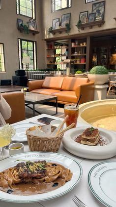 a woman sitting at a table with plates of food and drinks in front of her