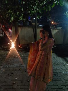 a woman standing next to a tree with her hand on her hip and light shining from behind