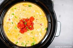 a black crock pot filled with soup and topped with diced red peppers on top