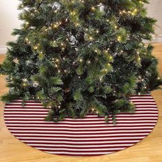 a christmas tree with lights on it sitting in front of a red and white striped rug