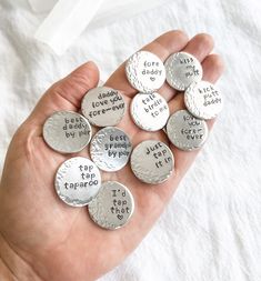 a person is holding several silver buttons with words on them that say i love you