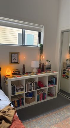 a bedroom with a bed, bookshelf and lamp on the wall next to it