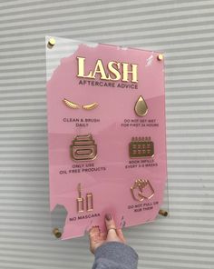 a person holding up a pink sign that says lash aftercare advice on it