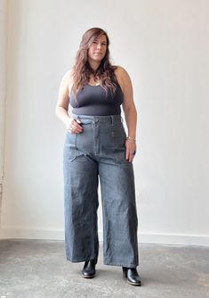 a woman standing in front of a white wall with her hands on her hips and wearing black shoes