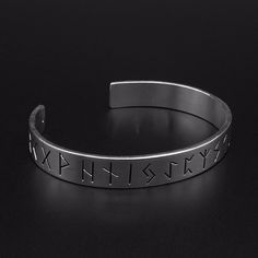 a silver bracelet with the words x and y on it, sitting on a black surface