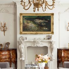 a living room filled with furniture and a chandelier above a fire place in front of a painting