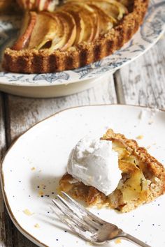 a piece of pie on a plate with a fork next to it and another pie in the background