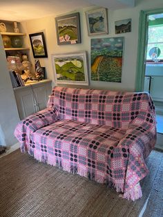 a living room filled with furniture covered in pink and black checkered fabric on top of carpeted flooring