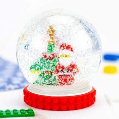 a snow globe sitting on top of a table next to legos and colored markers