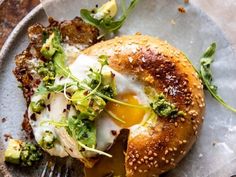 an egg and broccoli bagel on a plate with a fork