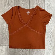 This Adorable Burnt Orange Lace-Trim Baby Tee From Hollister Is New Without Tags! Brown Cotton V-neck Top, Brown Cotton Crop Top, Casual Brown Crop Top, Trendy Brown Tops For Loungewear, Orange Baby, Hollister Tops, Garment Bags, Baby Tee, Infant Tees