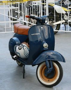 a blue motor scooter parked in front of a white fence