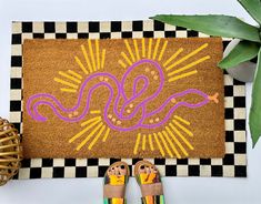 a pair of sandals sitting on top of a door mat next to a potted plant