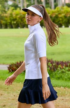 a female tennis player in a white shirt and blue skirt is walking on the grass