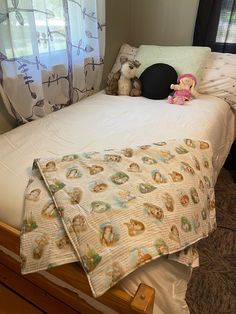 two teddy bears sitting on top of a bed in a room with curtains and windows